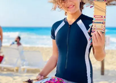الطفلة  «فاتيما» تبيع الإكسسوارات على الشاطئ