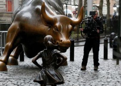 تمثالاً من البرونز لفتاة أمام تمثال برونزي شهير لثور وهي تنظر إليه بلا خوف