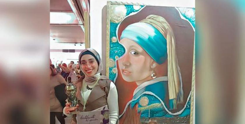 مريم حمزة مع إحدى لوحاتها الفنية