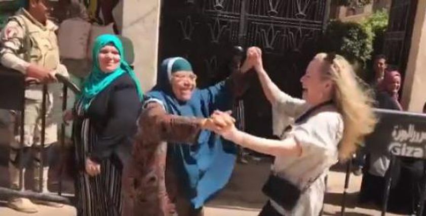 سيدة أمريكية ترقص مع إحدى السيدات المصريات من أمام اللجنة الانتخابية