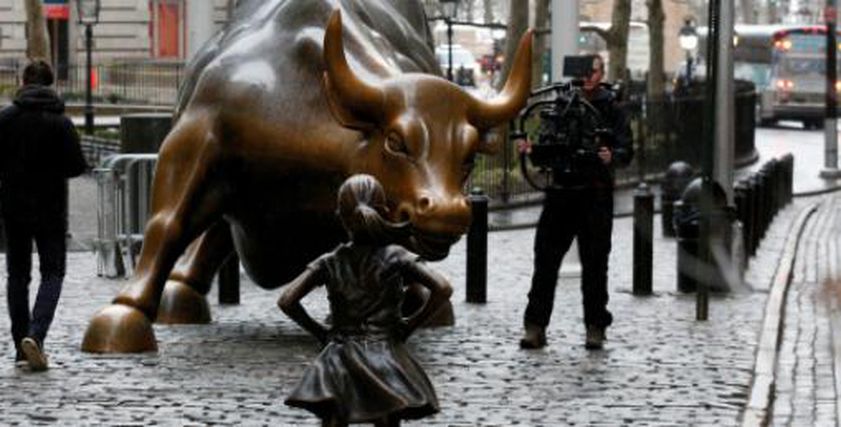 تمثالاً من البرونز لفتاة أمام تمثال برونزي شهير لثور وهي تنظر إليه بلا خوف