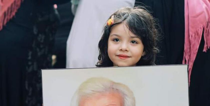 طفلة تحمل صورة جدها في إفطار المطرية