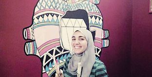 «مى» أمام أحد رسوماتها على الجدران