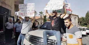 فلسطينيون يحملون لافتات فوق سيارة تقل وفداً أمريكياً فى القدس «أ. ف. ب»