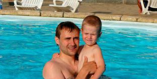 الأب المتهم "أوليج دراشيف" يحمل ابنه "إيليا" في حمام السباحة