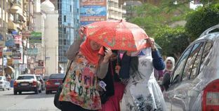 فتيات يحتمين من حرارة الشمس بمظلة