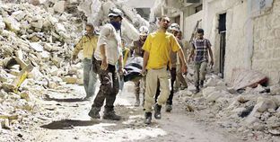 سوريون فى «حلب» أثناء نقل أحد الضحايا «أ.ف.ب»