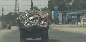 عربات حمل القمامة المكشوفة مستمرة فى إلقاء المخلفات بالطريق والأهالي للأحياء في حاجة اسمها غطاء.