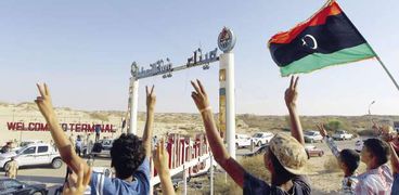 ليبيون يرفعون العلم الليبى أمام أحد موانئ تصدير النفط «أ.ف.ب»