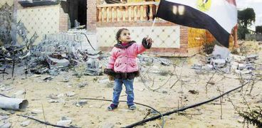 طفلة ترفع علم مصر أمام بيتها فى الشيخ زويد بعد عودتها إليه مع أسرتها