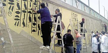 طلاب يرسمون نقوشاً فرعونية على الجدران