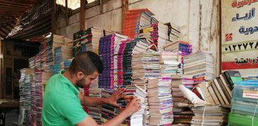 أحد الباعة يجهز «الكتب الخارجية» المستعملة لعرضها على المواطنين