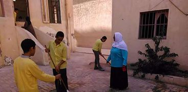 طلاب يشاركون فى تنظيف فناء مدرستهم