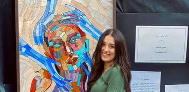 يارا عباس بجوار مشروع تخرجها وهي لوحة «الإنهيدونيا»