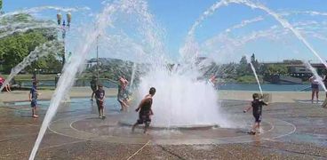 أطفال ومواطنون بمدينة اوريجون يحاولون الهروب من الحرارة بالاستحمام في نافورة