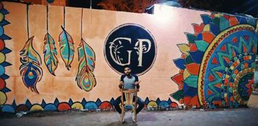 «كريم» مع إحدى رسوماته على الجدران