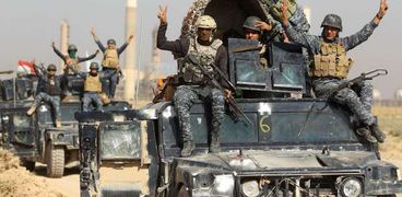 جنود عراقيون يرفعون شارات النصر بعد انتزاع أحد المواقع من قوات «البيشمركة» الكردية