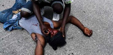 متظاهر ينزف من جرح على رأسه ملقى على الرصيف في هايتي