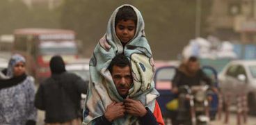 أب يحمي ابنه من العاصفة - تصوير محمد مدين