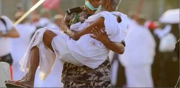 رجل أمن سعودي يحمل مسنا خلال أدائه مناسك الحج