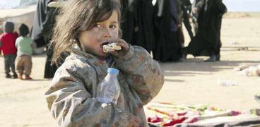 طفلة سورية تقضم قطعة خبز فى مشهد فرار عائلات سورية من مناطق القتال فى «باغوز» «أ.ف.ب»
