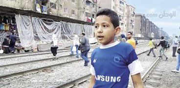 الطفل عبدالرحمن يمارس مهمته اليومية أمام «المزلقان»