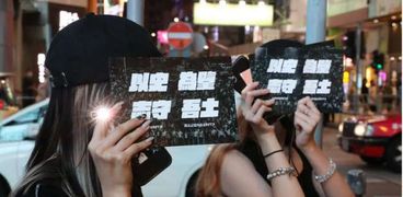 العشرات في هونج كونج يضيئون هواتفهم إحياء للذكرى «تيان أنمين»