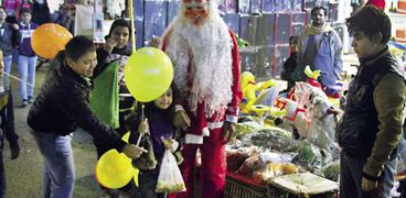 البائع مرتدياً ملابس بابا نويل وحوله الأطفال