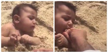 أب يدفن طفله في الرمل