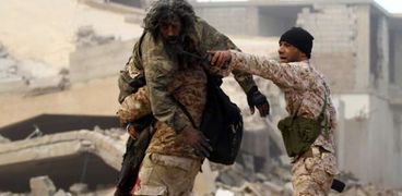 جندي ليبي يحمل أحد الأسرى المحررين في قنفودة غربي بنغازي