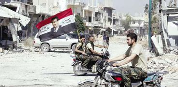 جنود سوريون يحملون العلم السورى مزيناً بصورة «بشار»