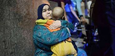 فايزة تحمل ابنها عبدالرحمن أمام معهد الأورام