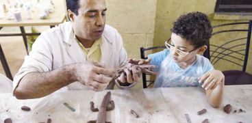 «مجدى» يعلم طفلاً فن النحت على الخذف