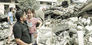 فلسطينى وابنته يبكيان بجوار منزلهما المنهار جراء الغارات الإسرائيلية