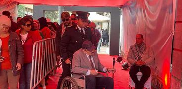 ضابط شرطة يساعد أحد كبار السن على الإدلاء بصوته في انتخابات الرئاسة