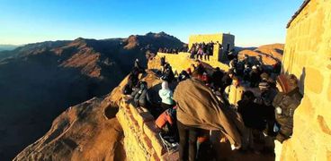 السياح يشاهدون شروق الشمس من قمة جبل موسي
