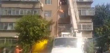 بالفديو| رجل صينى حجه 225 كجم.. استخدام رافعة بناء لإنزاله من شقته