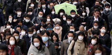 مواطنون يسيرون في أحد شوارع طوكيو الرئيسية مع الالتزام بارتداء الكمامة