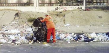 عامل النظافة يلقى القمامة فى الشارع
