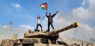 فلسطيني يرفع علم دولته على دباية إسرائيلية مدمرة
