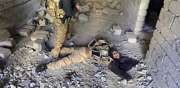 جندى عراقى بجوار جثة داعشى بعد تصفيته «أ.ف.ب»