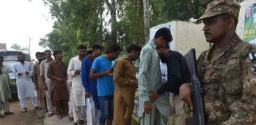 شرطي باكستاني يفتش الناخبين خارج مركز اقتراع في لاهور صباح اليوم