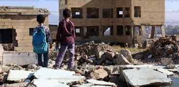 أطفال بنظرون إلى أطلال مدرستهم بعد تدميرها بسبب الحرب في اليمن