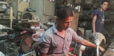 «محمد» خلال صيانة الأجهزة الكهربائية داخل ورشته