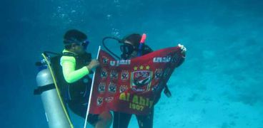 آدم يحمل علم الأهلي تحت الماء