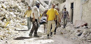 سوريون فى «حلب» أثناء نقل أحد الضحايا «أ.ف.ب»