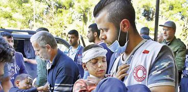 رجال الإسعاف أثناء نقل أطفال سوريين مصابين «أ.ف.ب»