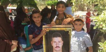 أطفال يحملون صورة الشهيد محمد عيسى العليمي أثناء جلسات محاكمة قاتليه