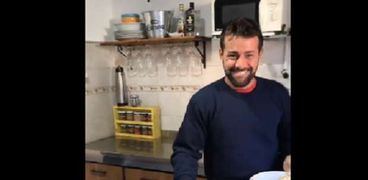 رجل يحمل في يده أطباق الطعام في مقطع من فيديو الأغنية الإسبانية Mi mujer me gobier