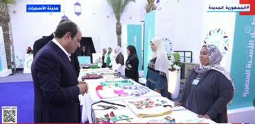 الرئيس عبدالفتاح السيسي وإحدى المشاركات بمعرض الأسر المنتجة بالأسمرات